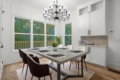 Bright dining room with large windows, black chandelier, and a gray table set for four