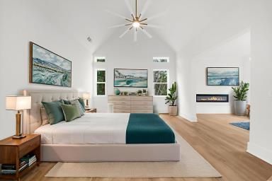 Bright modern bedroom with white walls, wood floors, teal accents, and ocean artwork