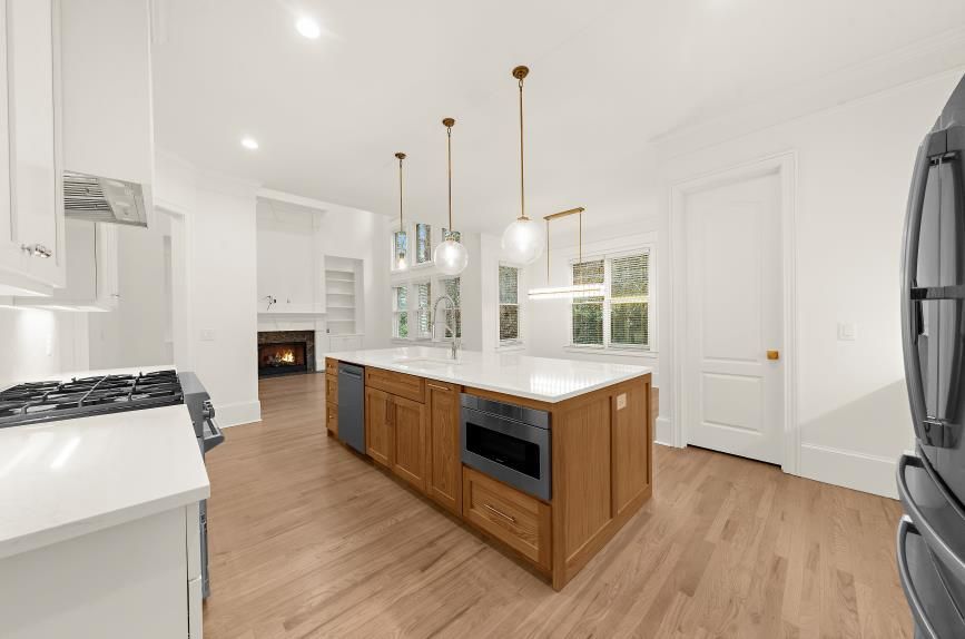 Bright white kitchen with wood island, pendant lights, and hardwood floors