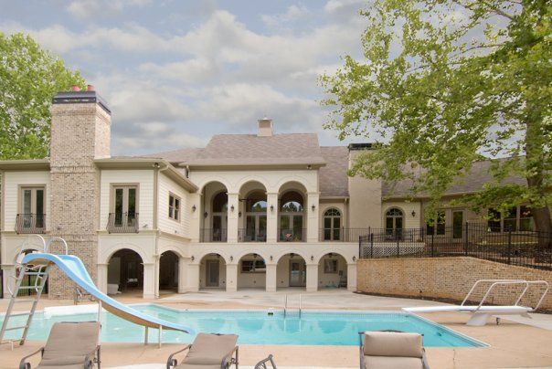 Luxury resort courtyard with pool, stone building, arched balconies, and blue waterslide