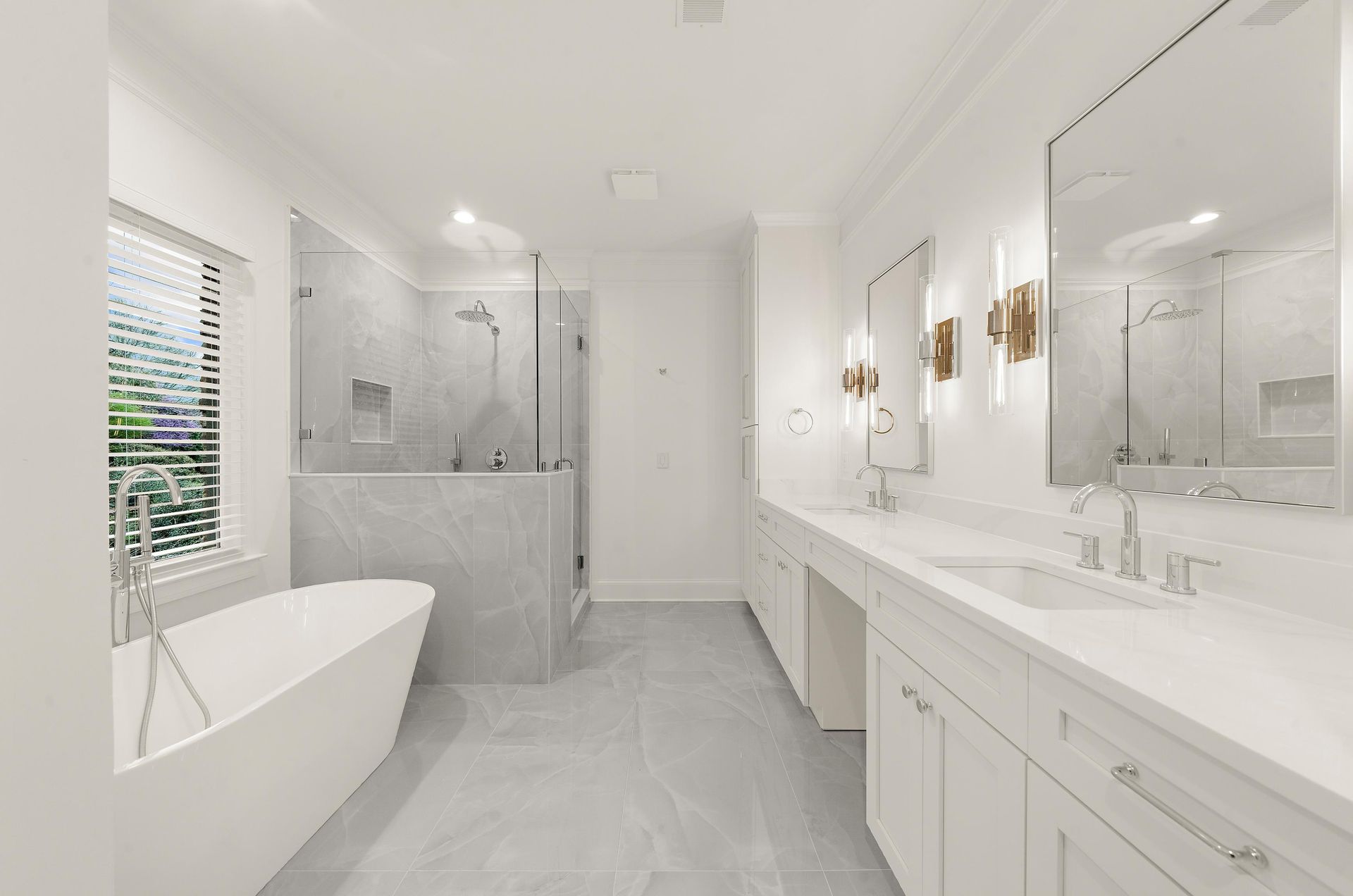 Bright white modern bathroom with freestanding tub, double vanity, and glass shower.