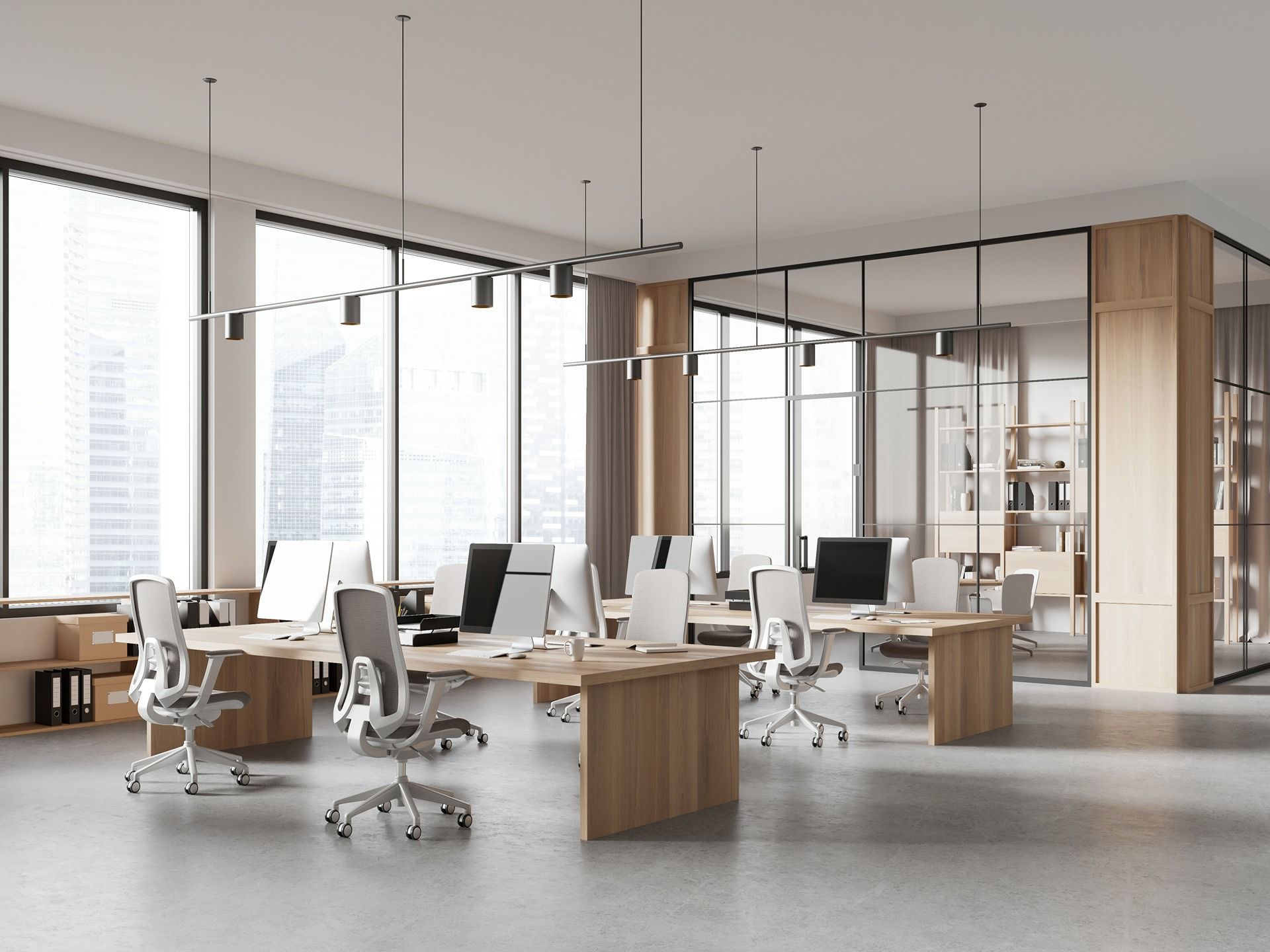 Modern open-plan office with desks, swivel chairs, and large windows letting in bright daylight
