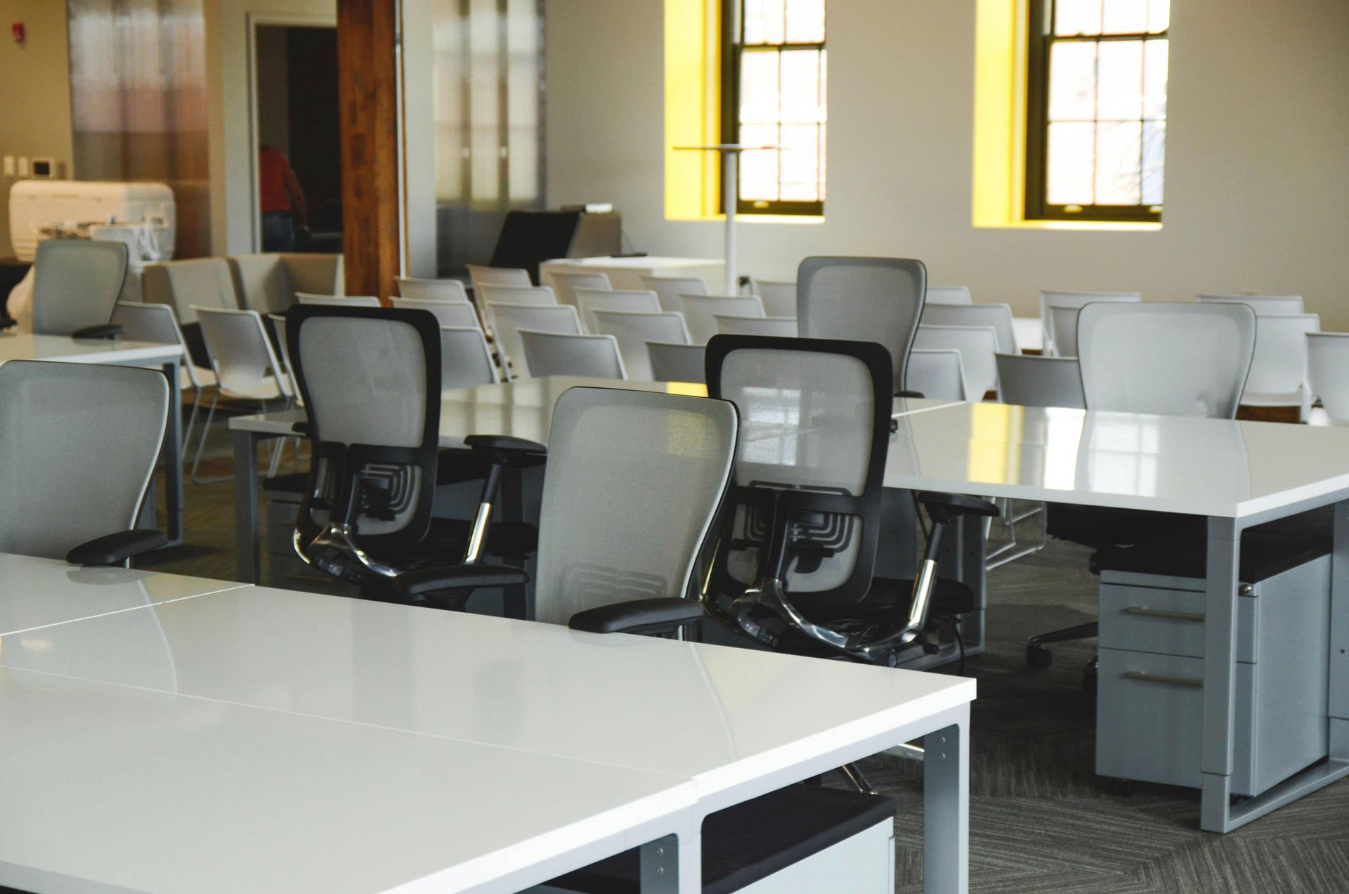 Empty office break room with tables and chairs by sunlit windows