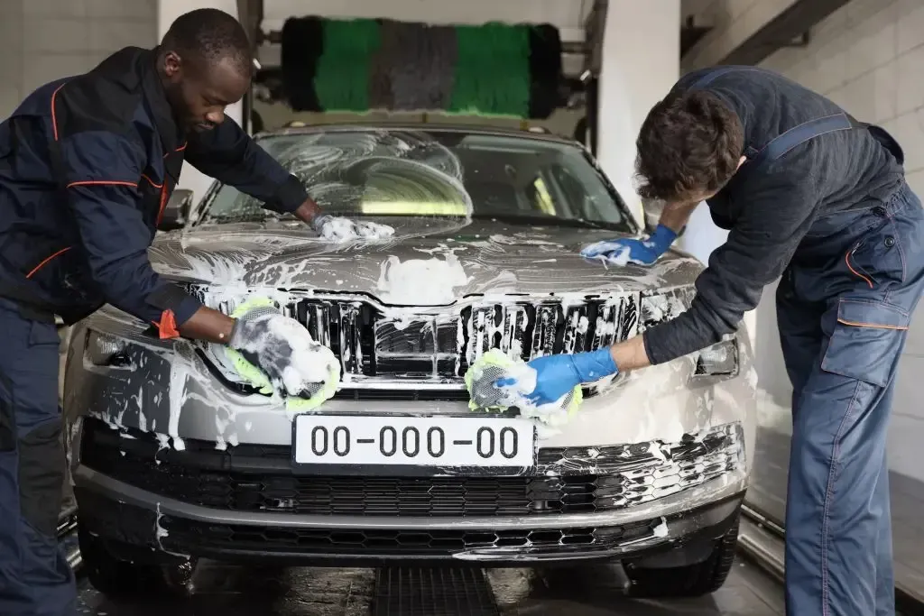 Two men are washing a car in a car wash.