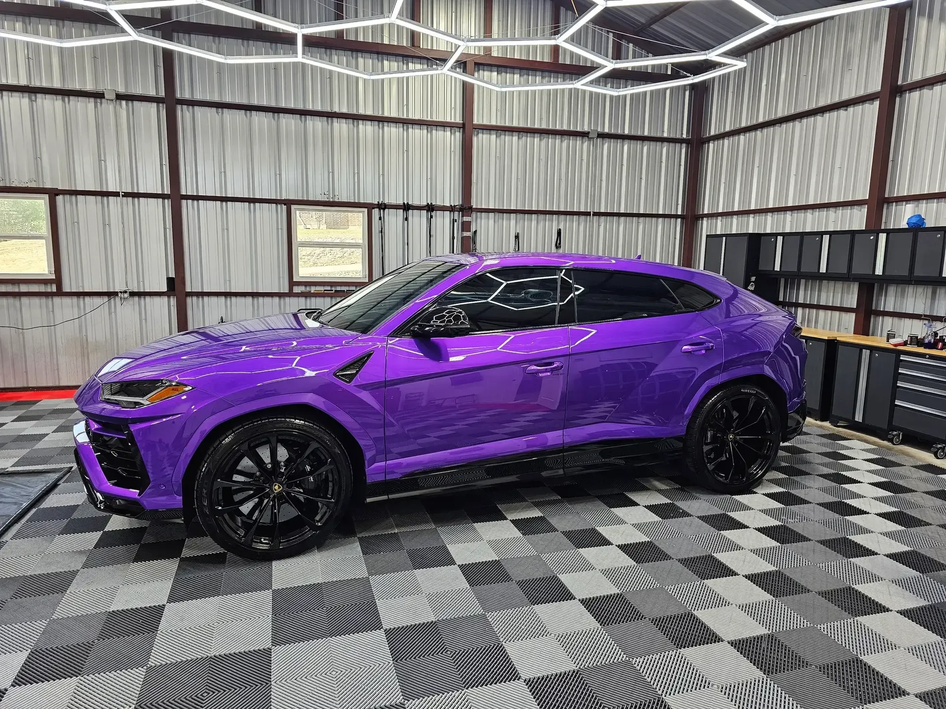 A purple lamborghini urus is parked in a garage.