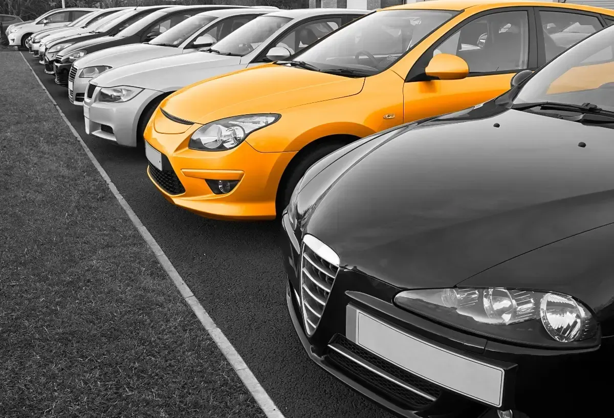 A row of cars are parked in a parking lot.