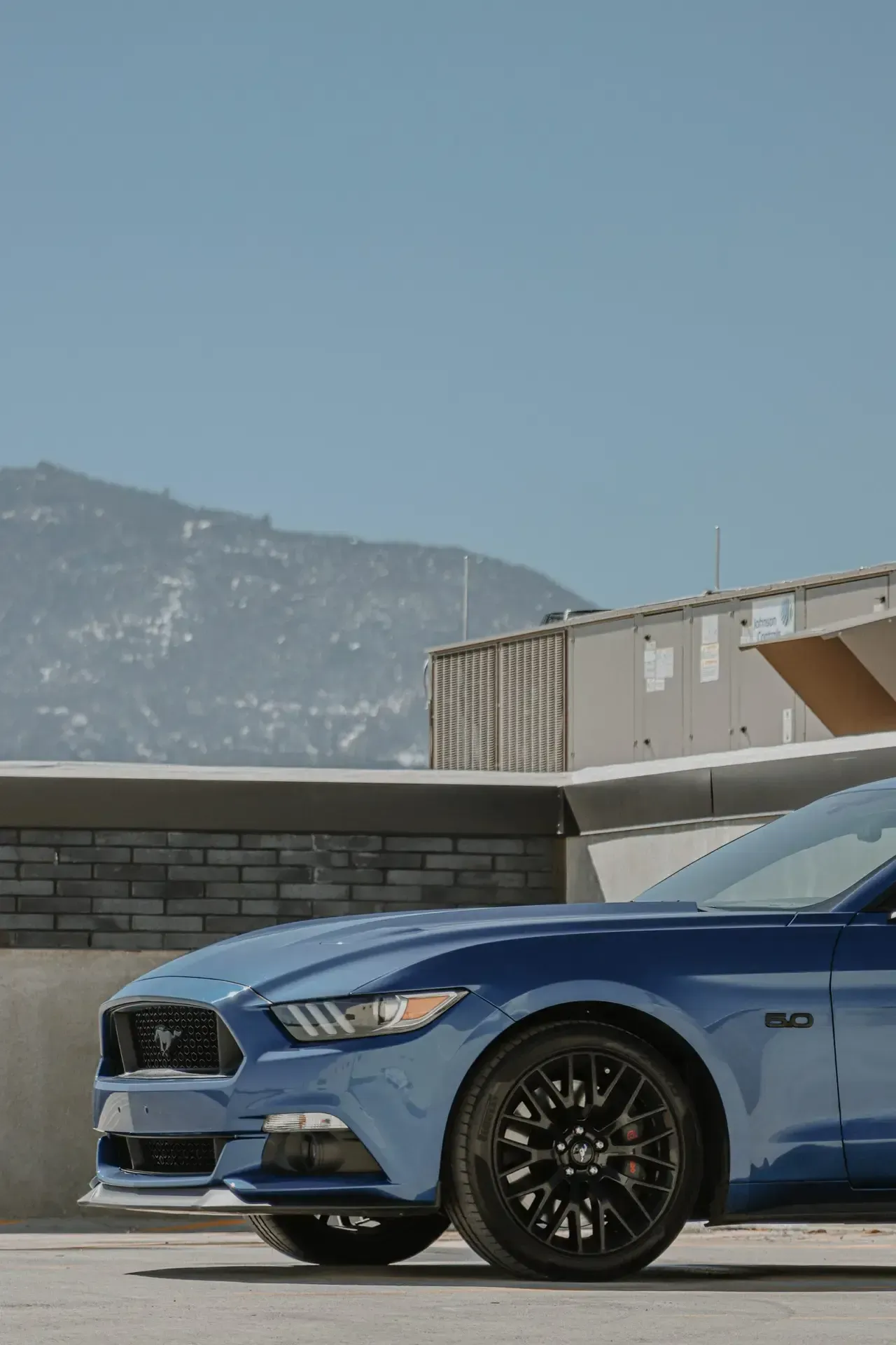 A blue ford mustang is parked in a parking lot.