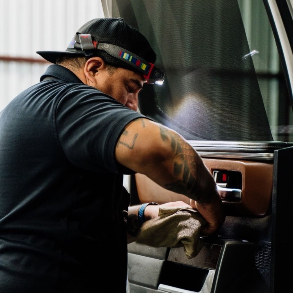 Mechanic cleaning a car dashboard with a cloth inside a vehicle