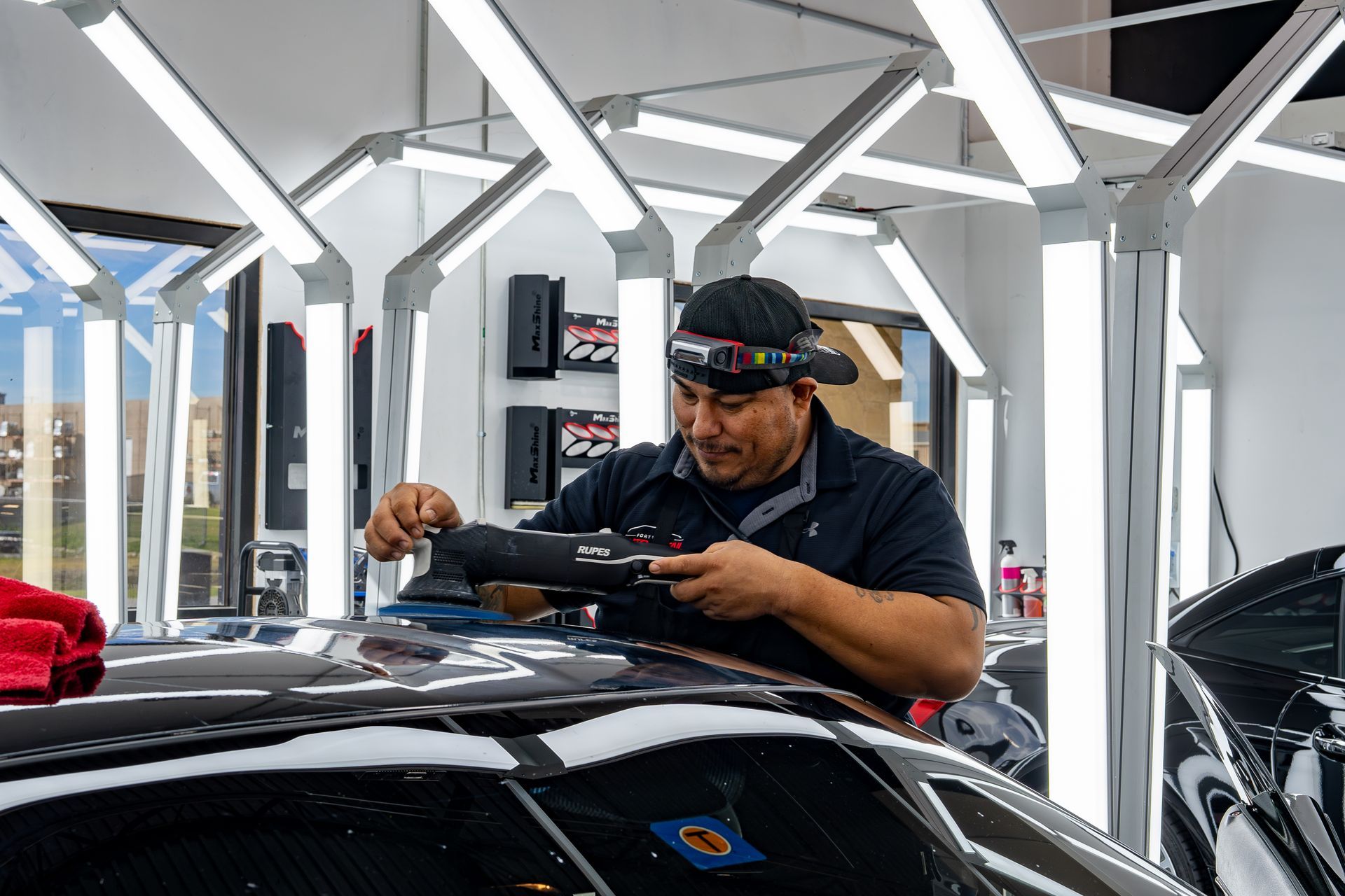 A man is working on the roof of a car in a garage.