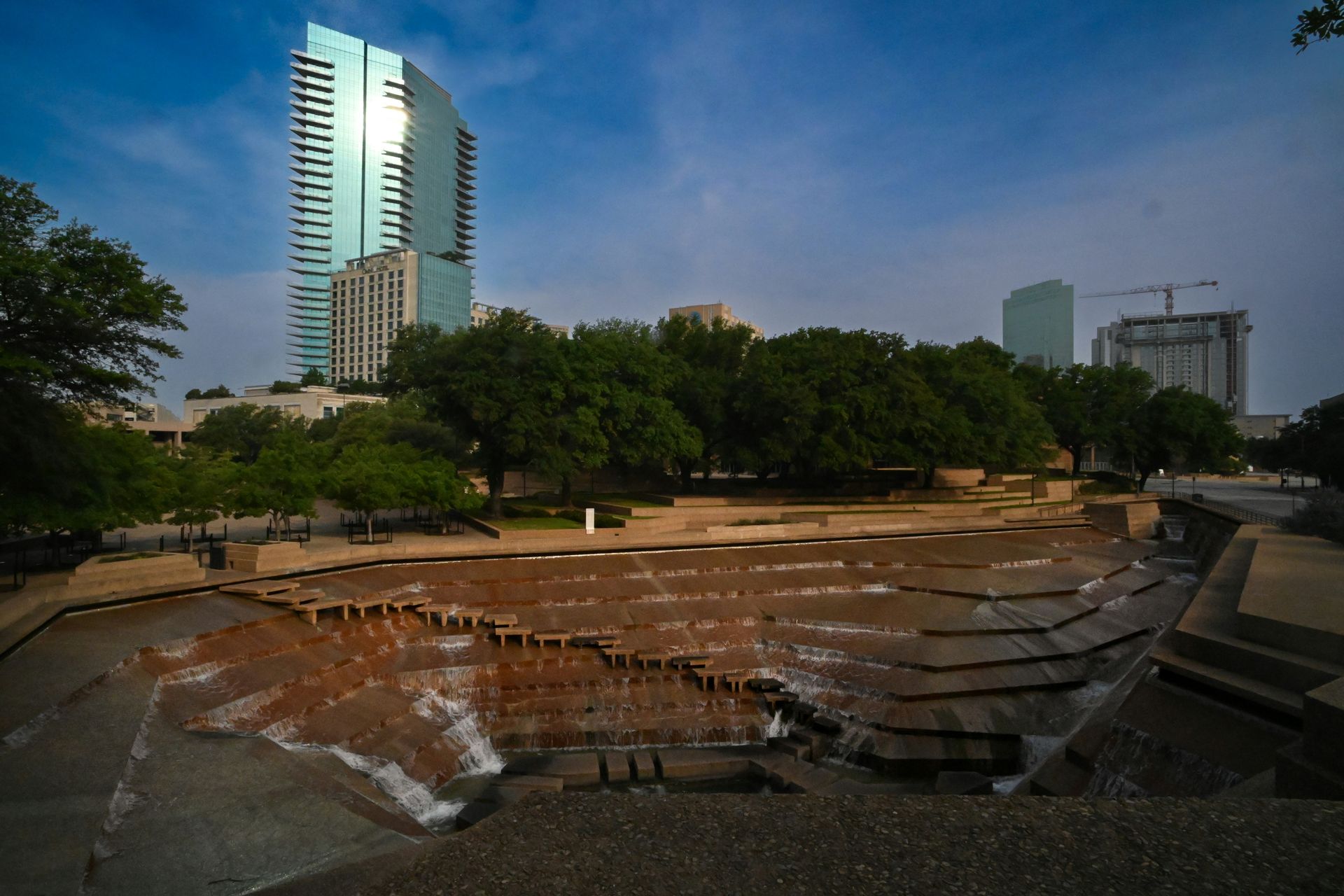 A fountain in a park with a tall building in the background