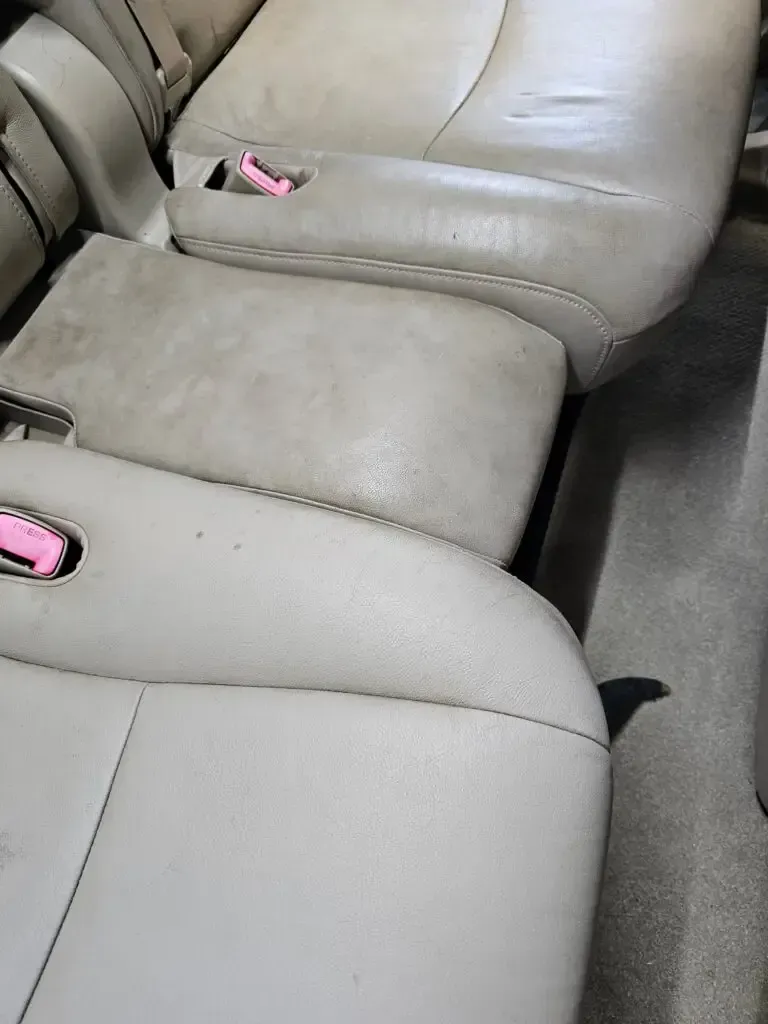 A close up of the back seat of a car with a pink buckle.
