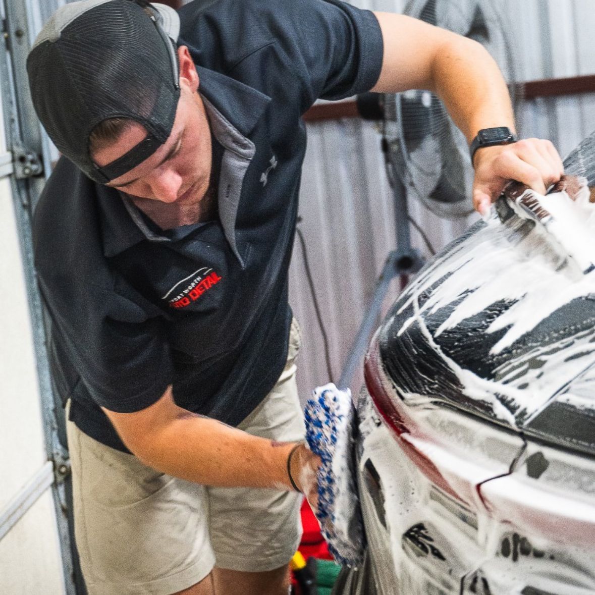 Detailer polishing a white car in a garage with a microfiber cloth