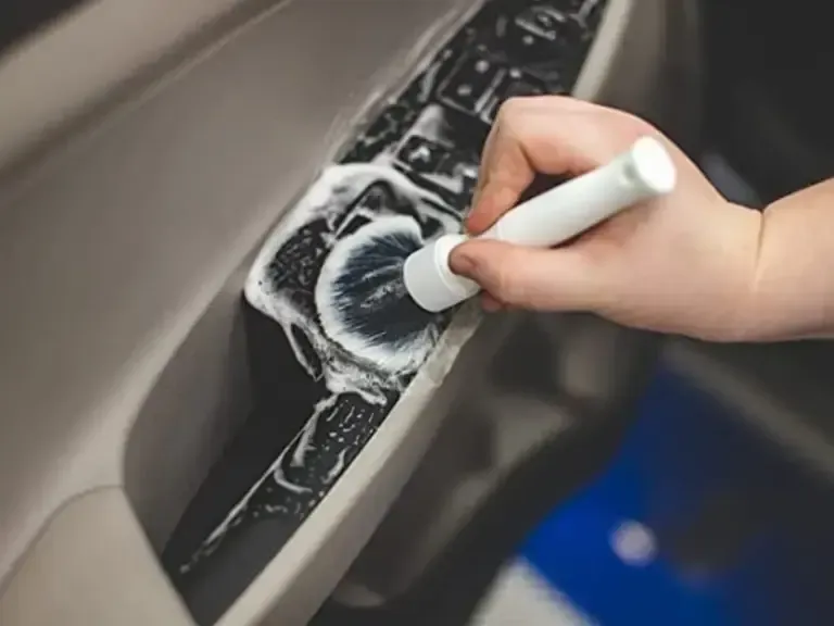 A person is cleaning a car door with a brush.