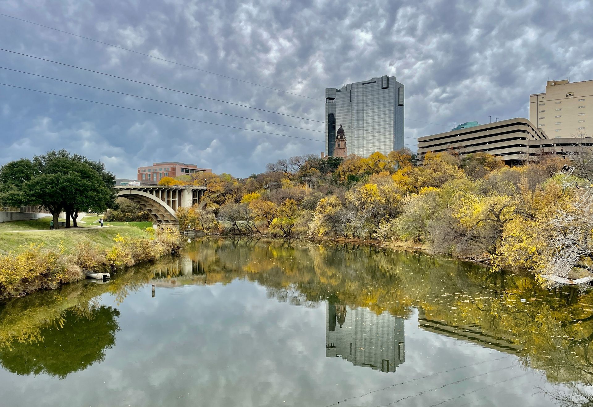 A river surrounded by trees and buildings with a bridge in the background.