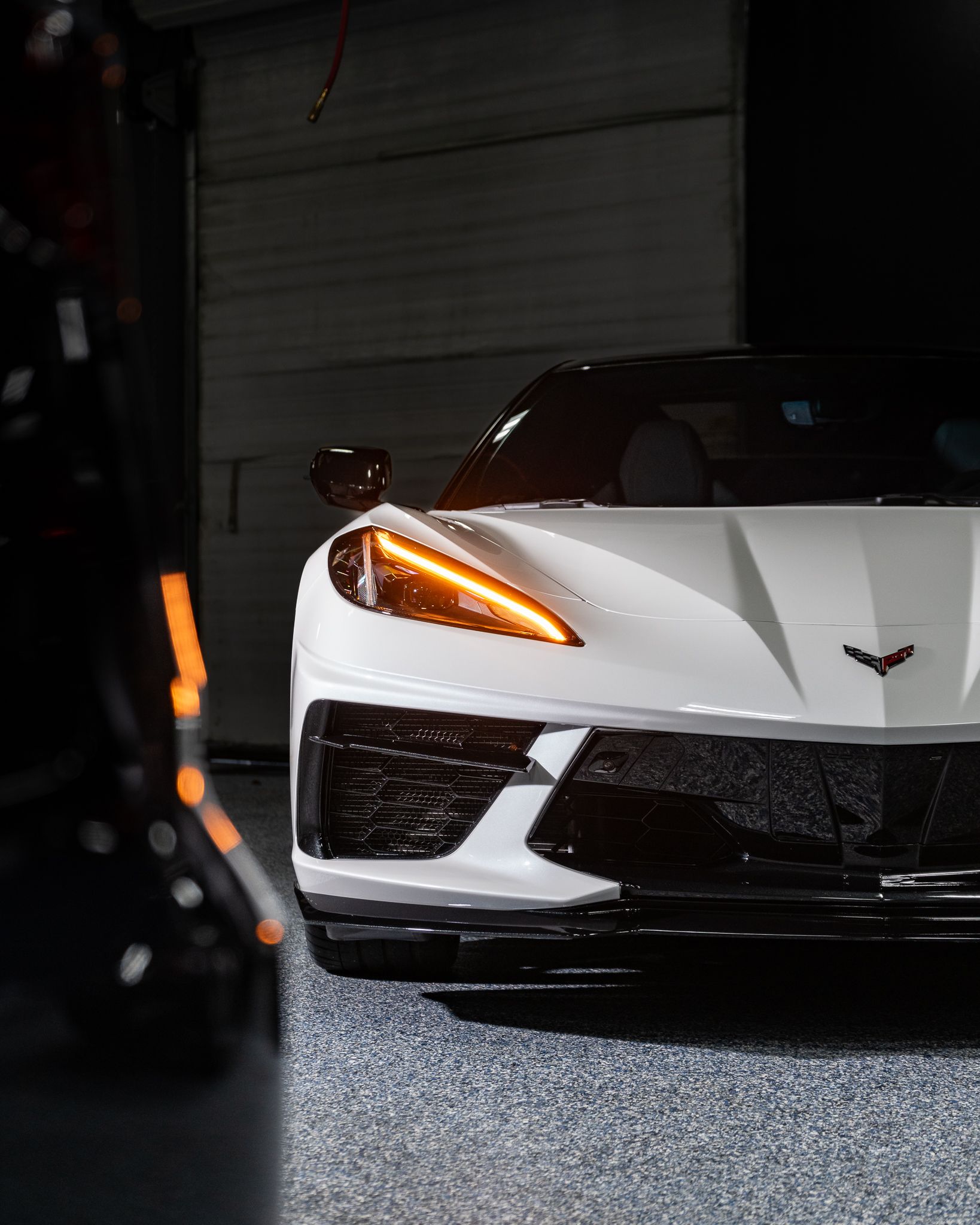 A white corvette is parked in a garage.