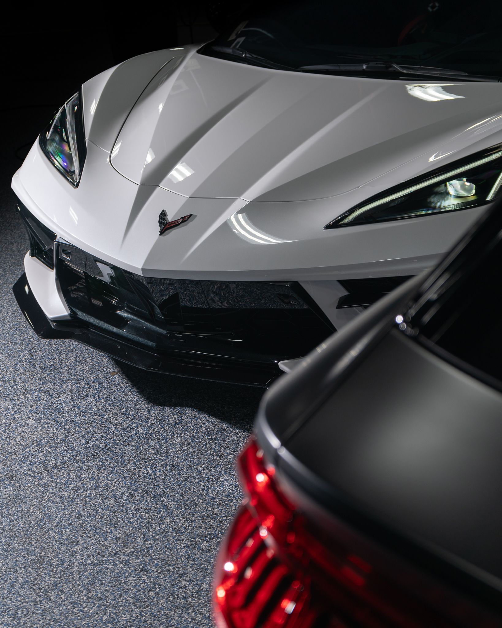 A white corvette is parked next to a silver car
