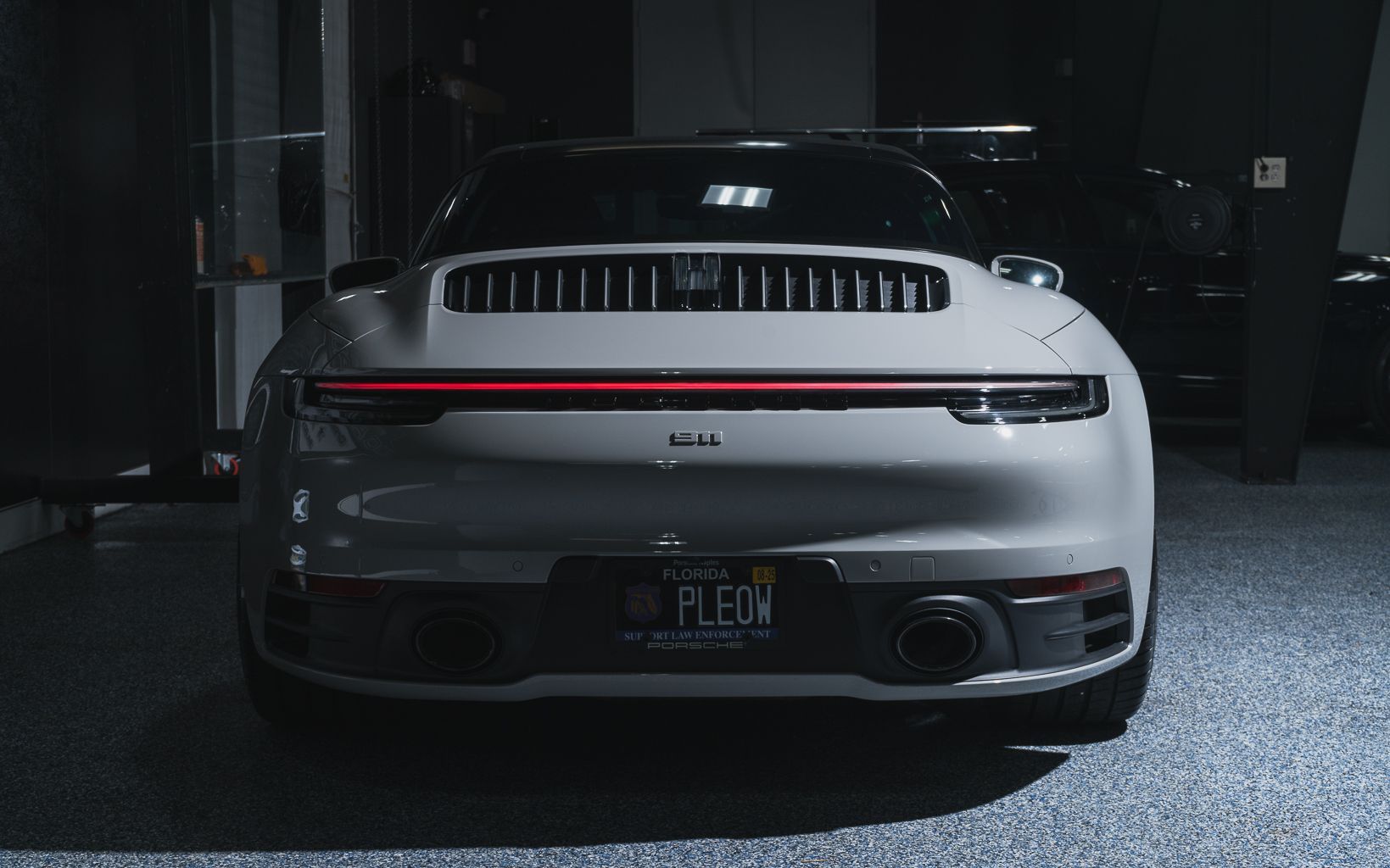 A white porsche 911 is parked in a dark garage.