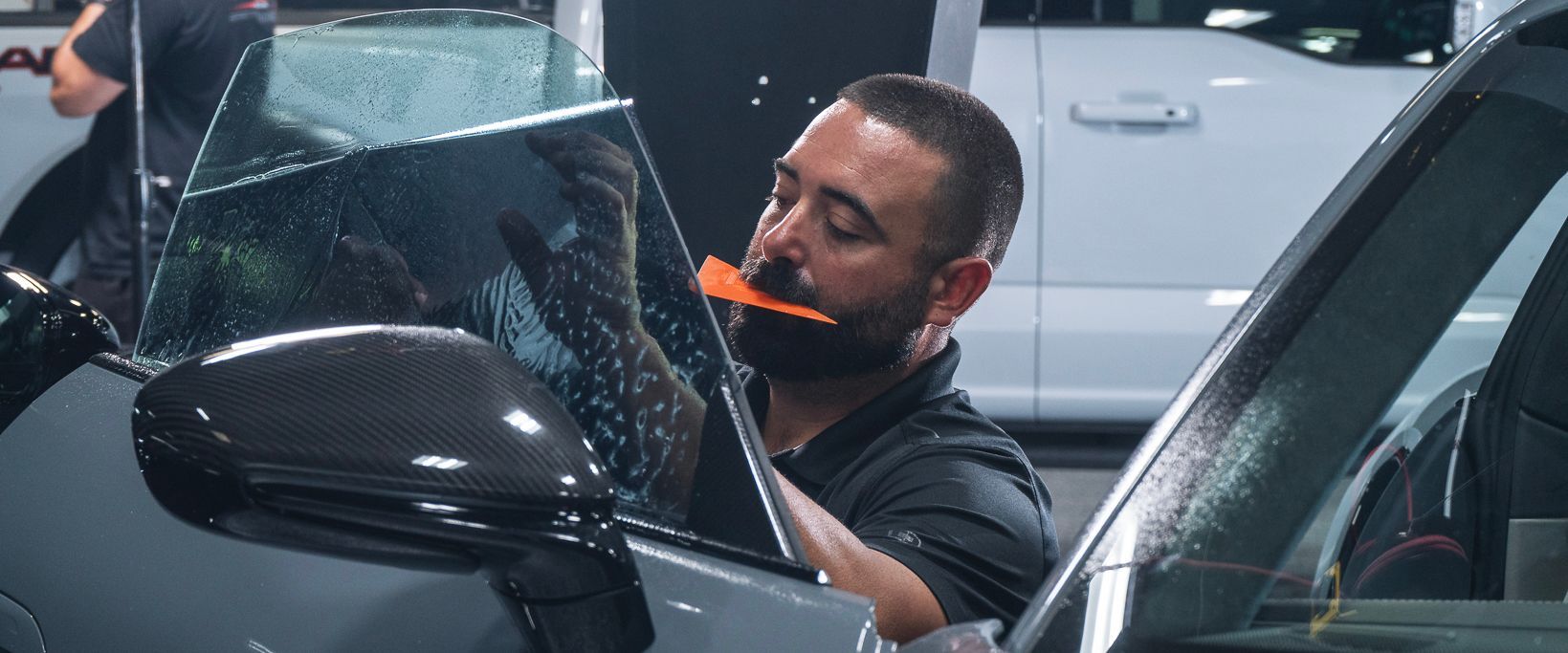 A man is applying window tinting to a car window.