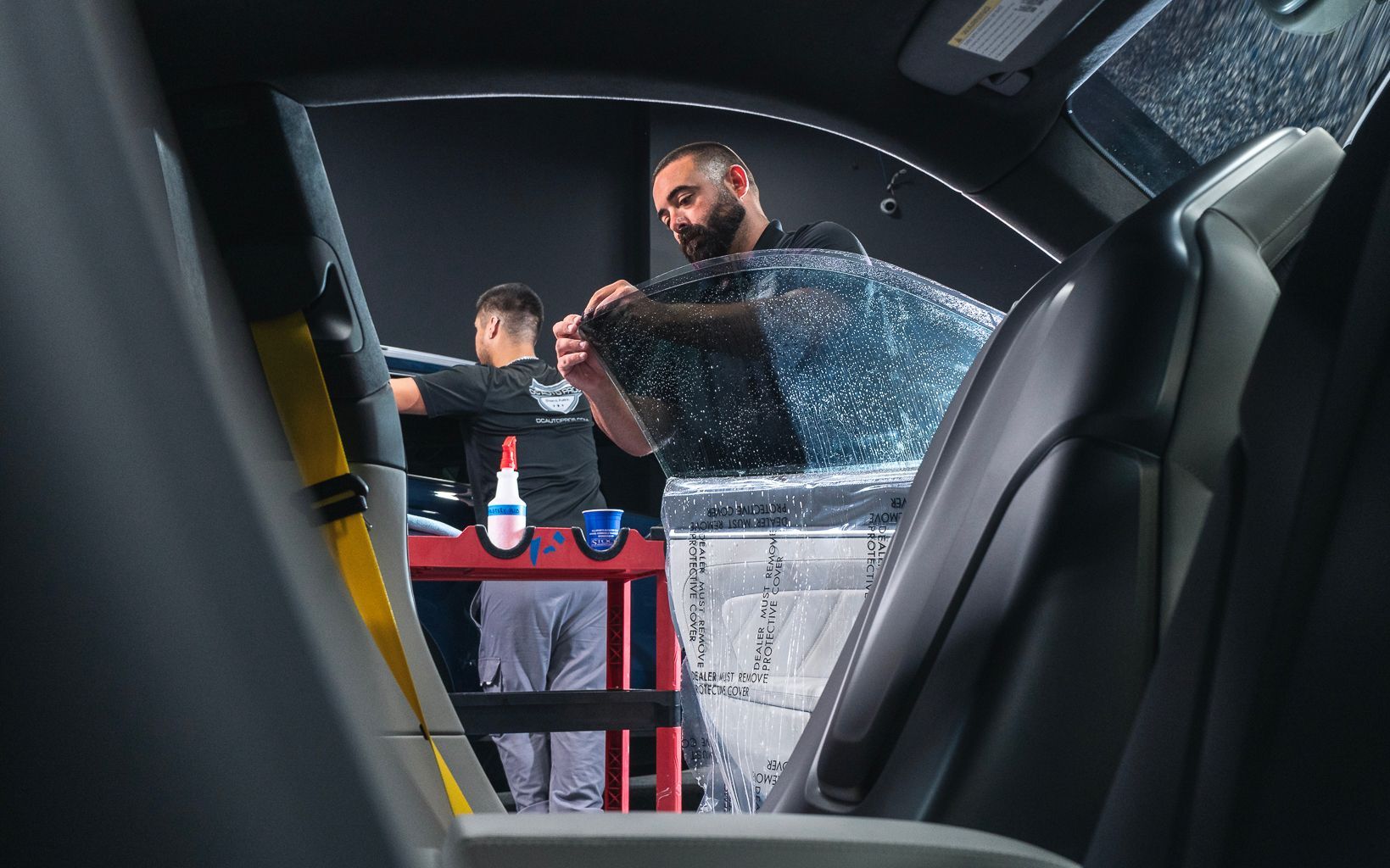 A man is applying window tinting to a car window.