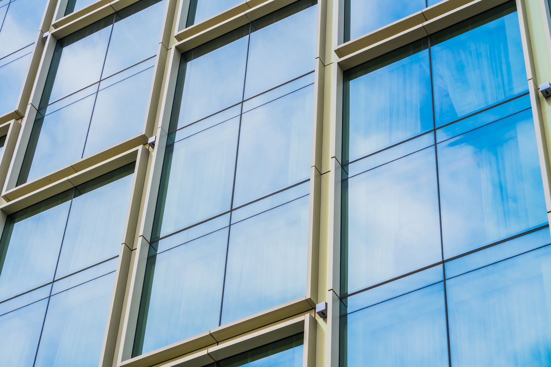 A close up of a building with a lot of windows and a blue sky reflected in the windows.