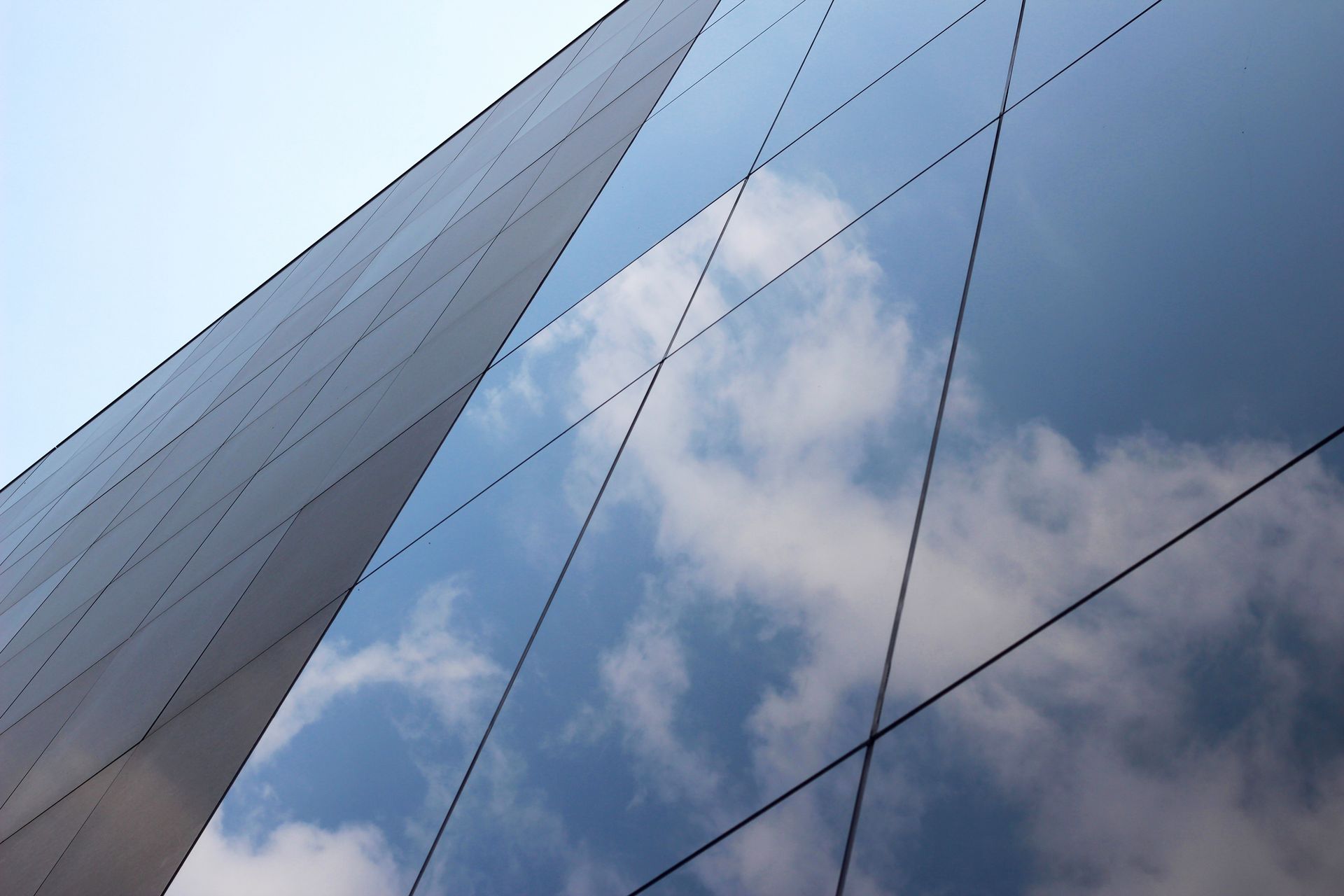 Looking up at a building with clouds reflected in the windows