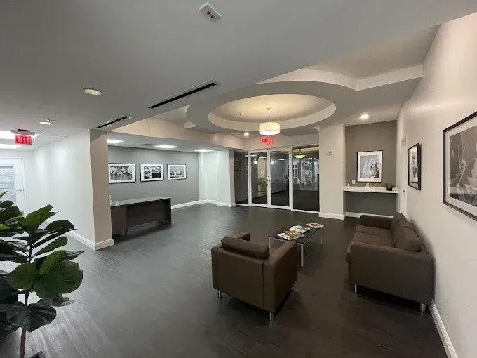 Interior of a modern lobby with seating, artwork, and recessed lighting. Dark floors and gray walls.