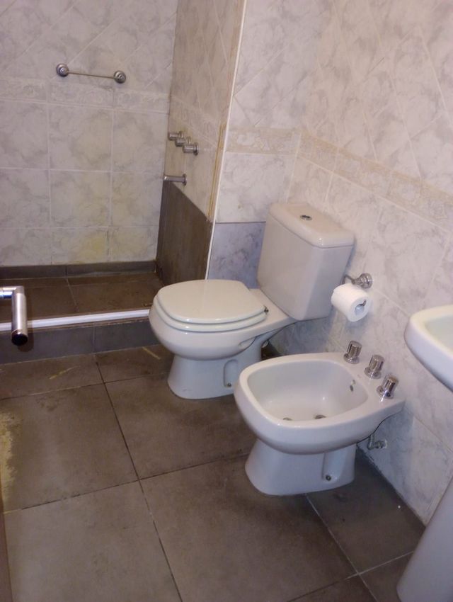 Manos usando una llave inglesa para reparar el desagüe de un lavabo debajo de un lavabo de baño