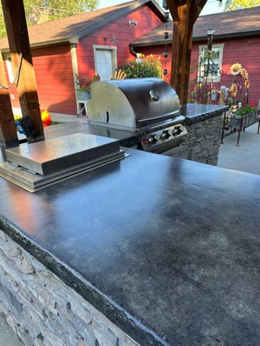 A grill is sitting on top of a counter in front of a red house.