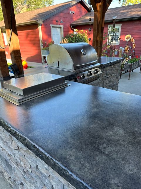 A grill is sitting on top of a counter in front of a red house.