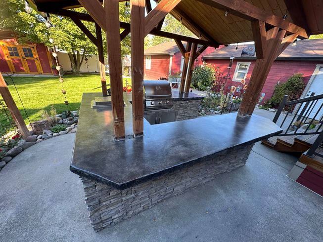 A kitchen with a large table and stools and a grill.