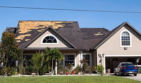 House with significant roof damage; missing shingles exposing the underlayment.