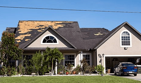 House with significant roof damage; missing shingles exposing the underlayment.