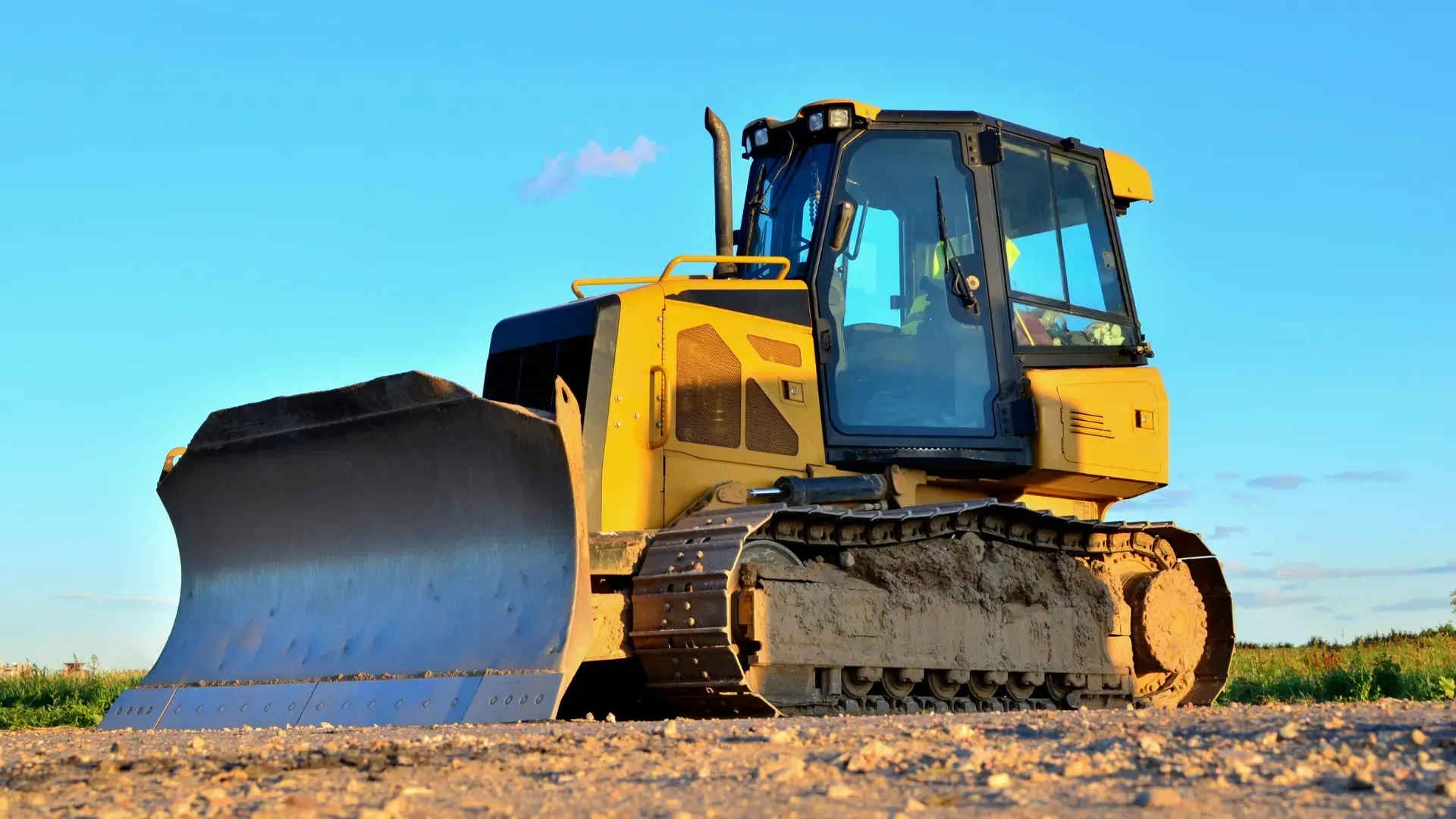 Yellow bulldozer on a construction site with a blue sky background.