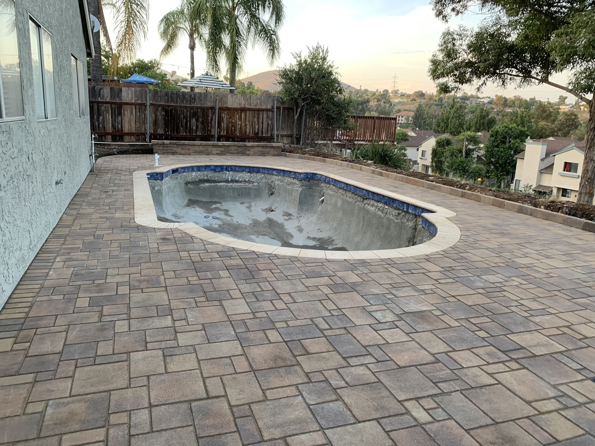 A brick patio with a swimming pool in the middle