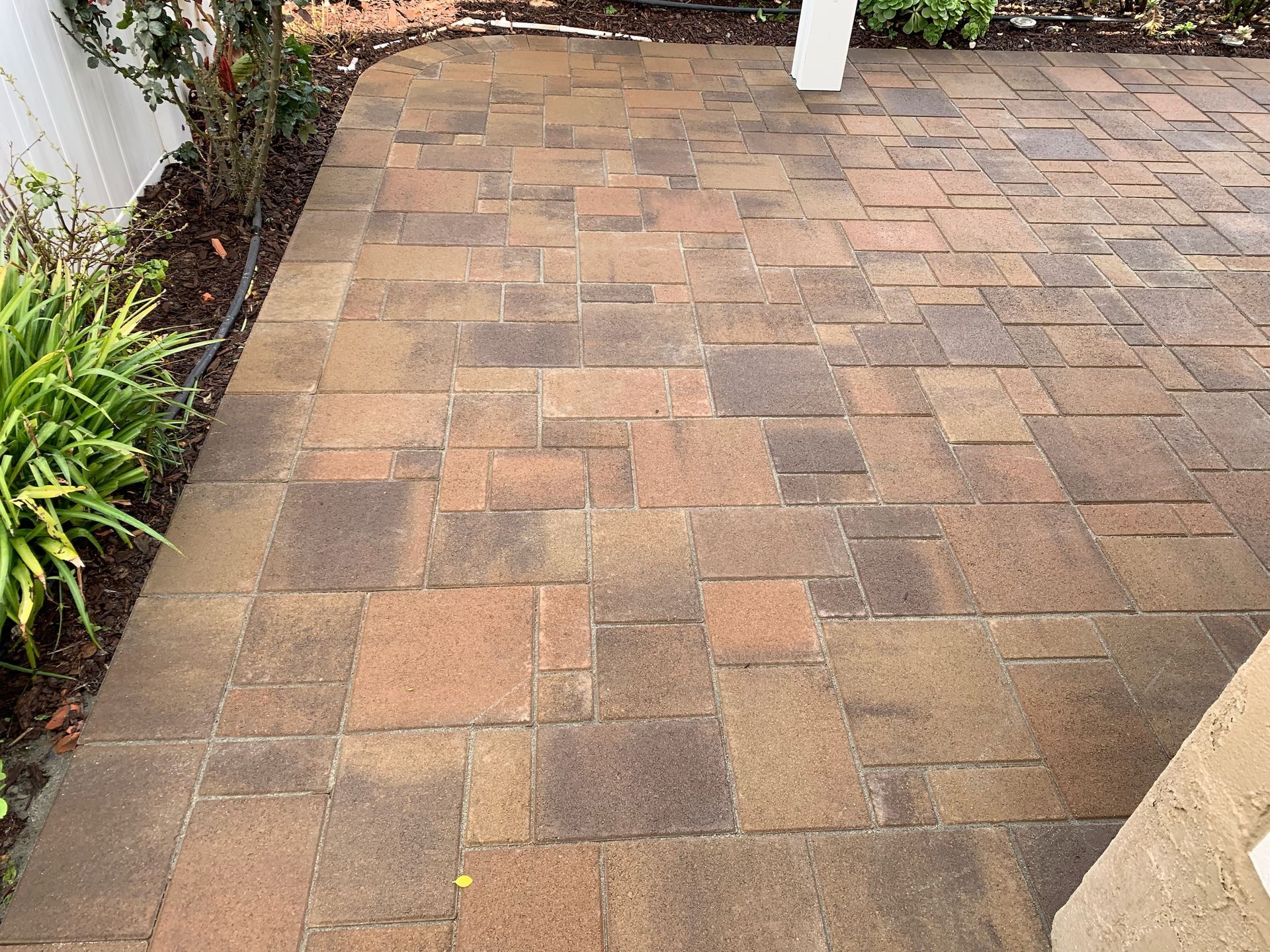 A brick walkway with a white pergola in the background