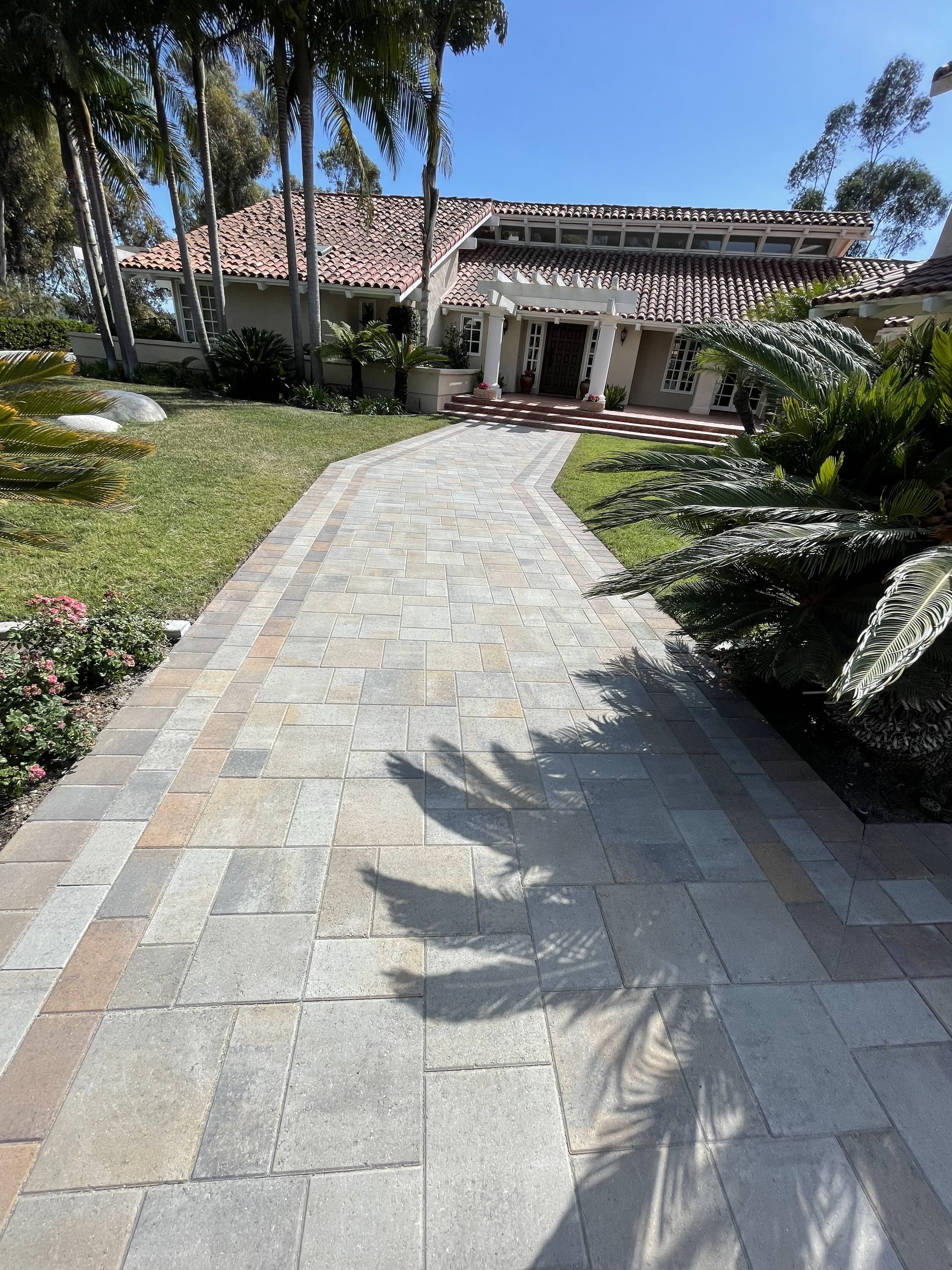 A brick walkway leading to a large house
