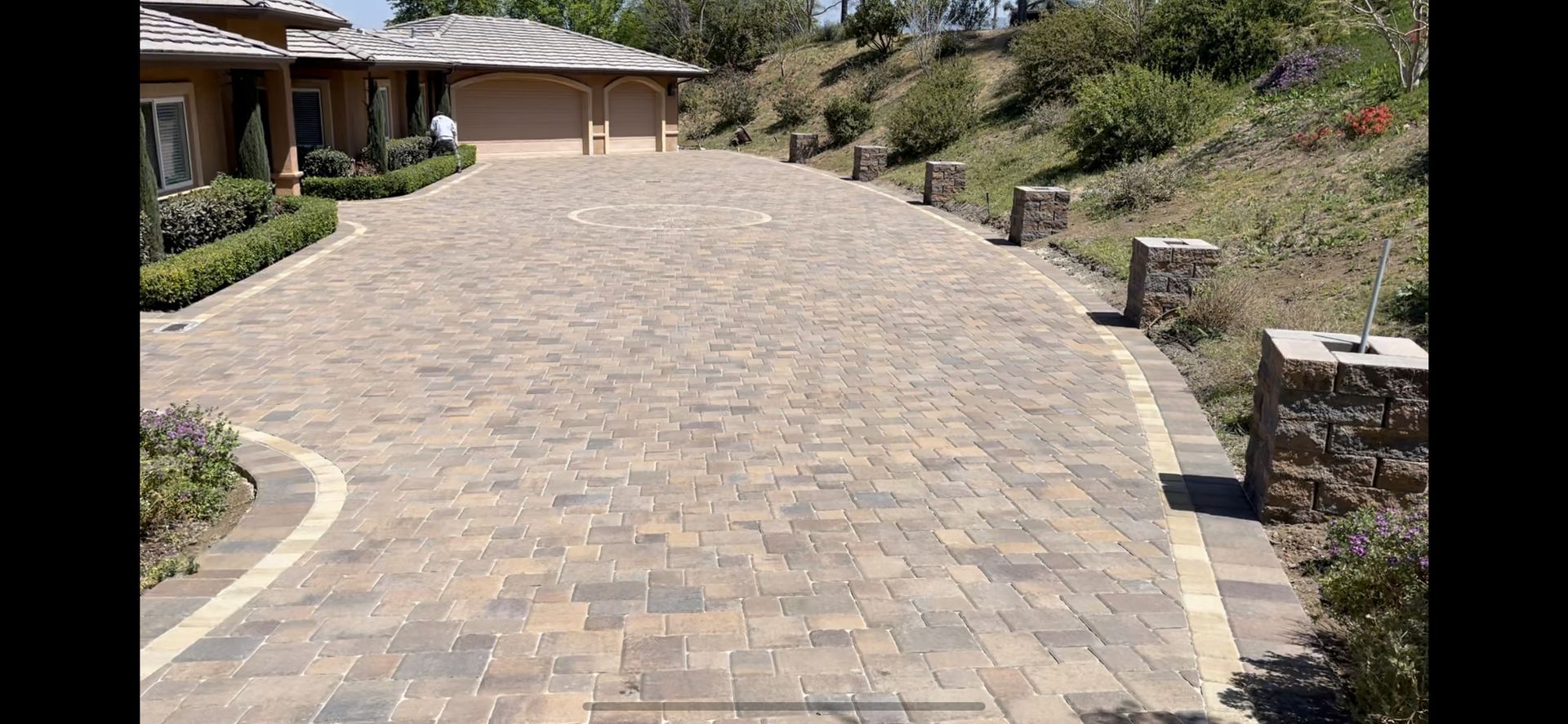 A brick driveway leading to a house on a hill
