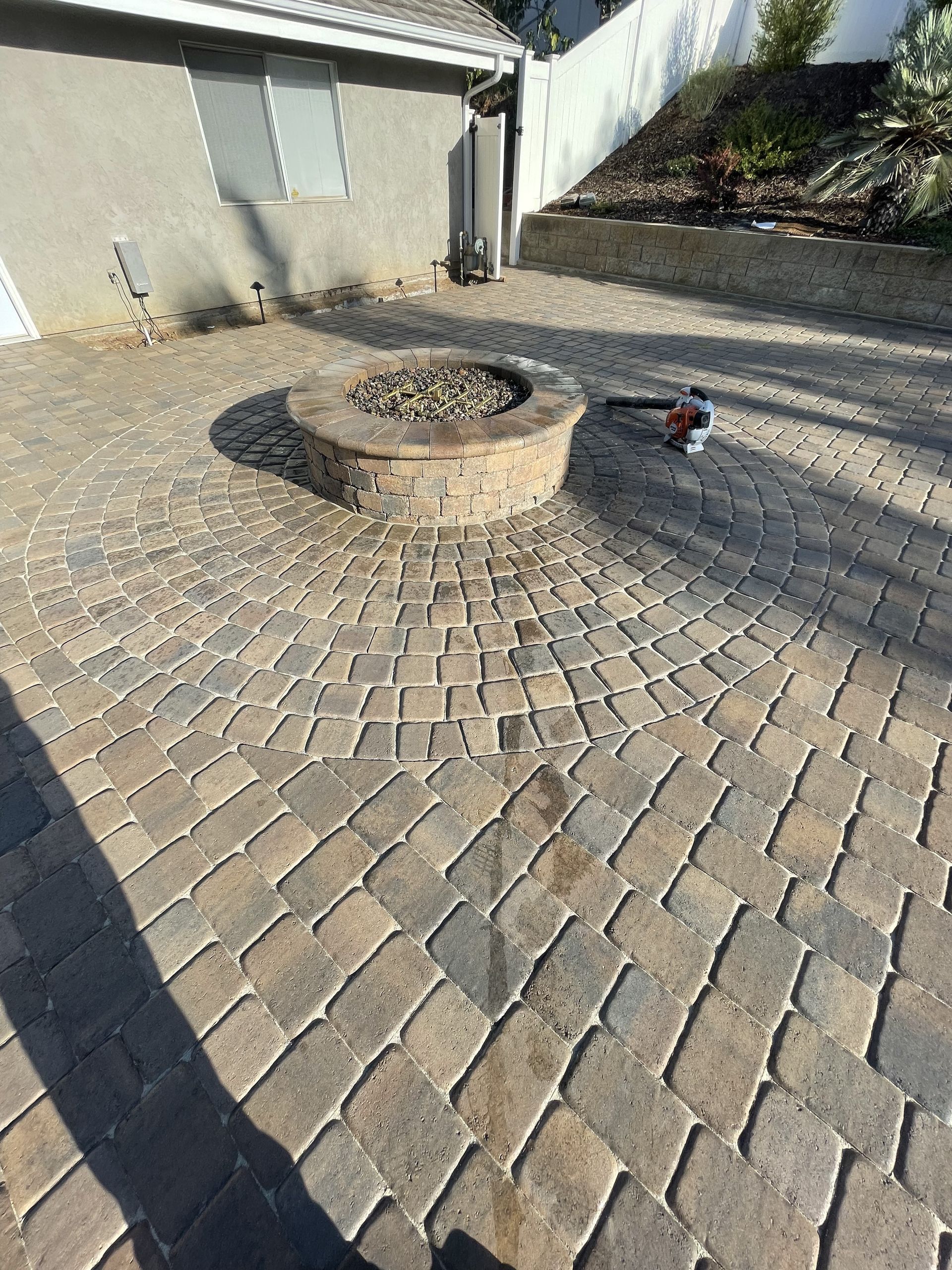 A brick patio with a fire pit in the middle