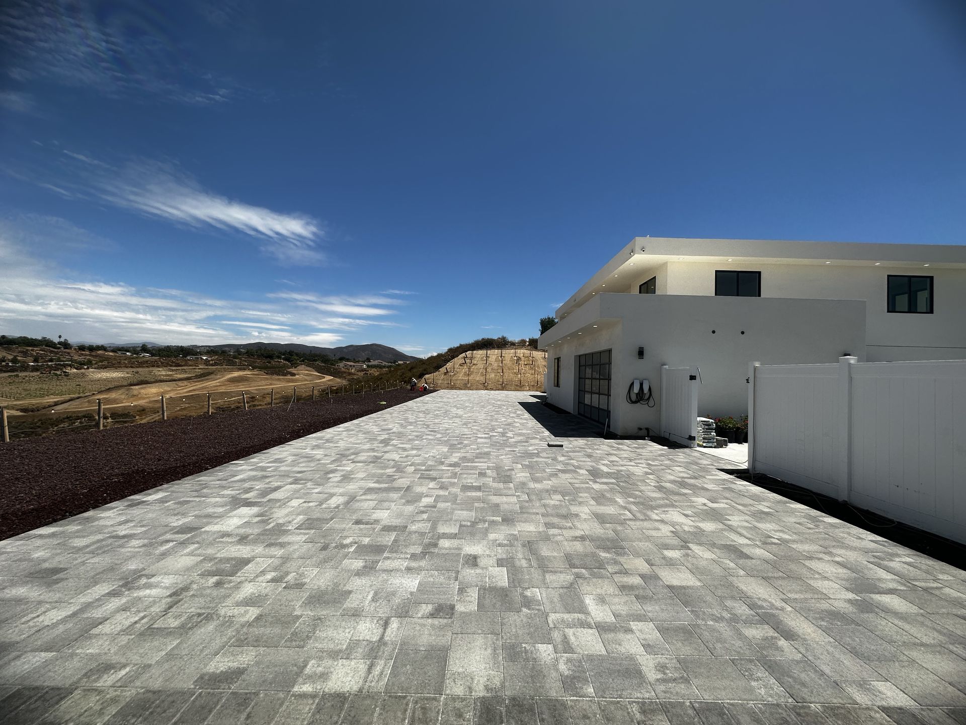 A brick driveway leading to a large white house