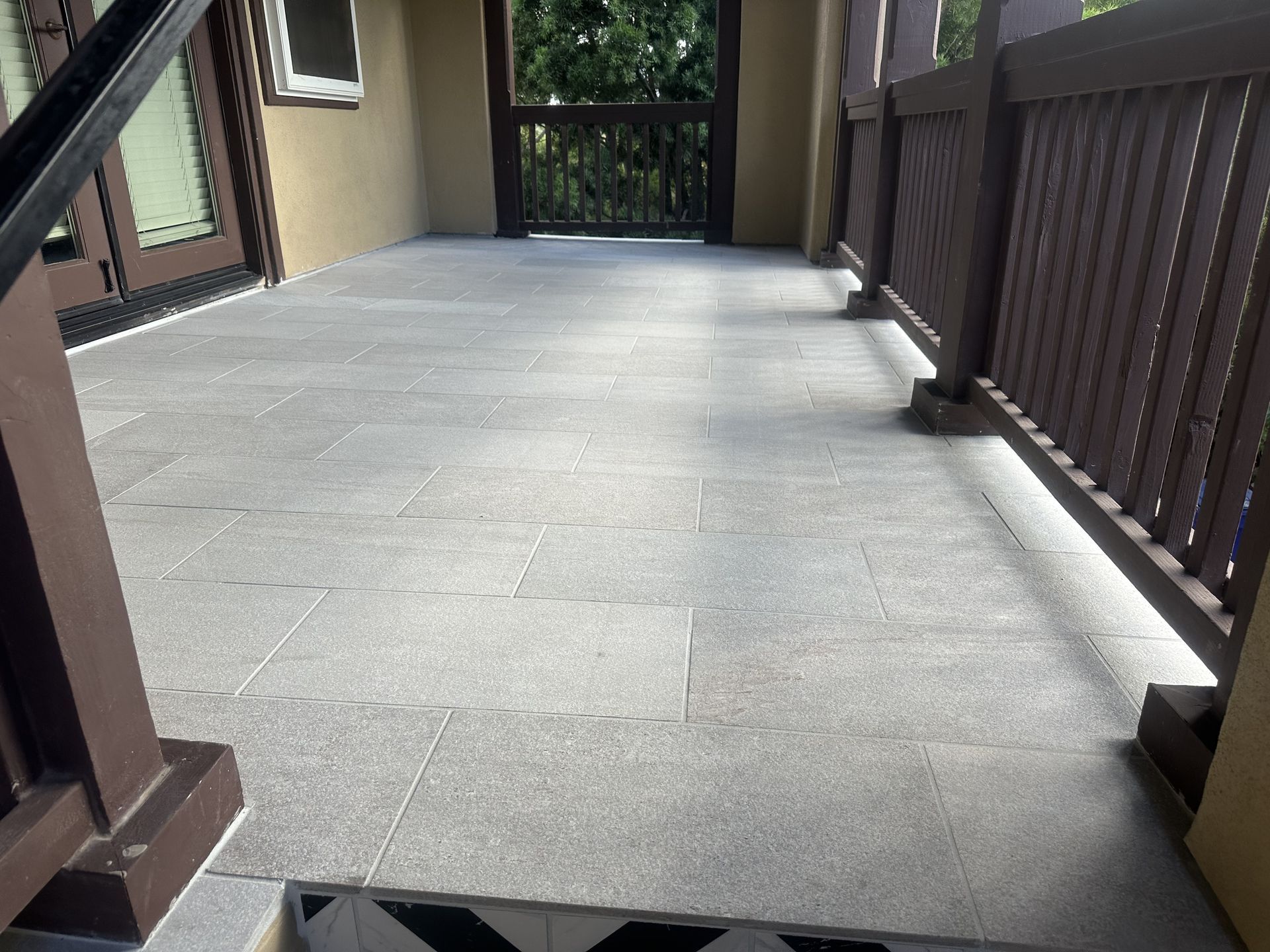 A balcony with a wooden railing and a tiled floor