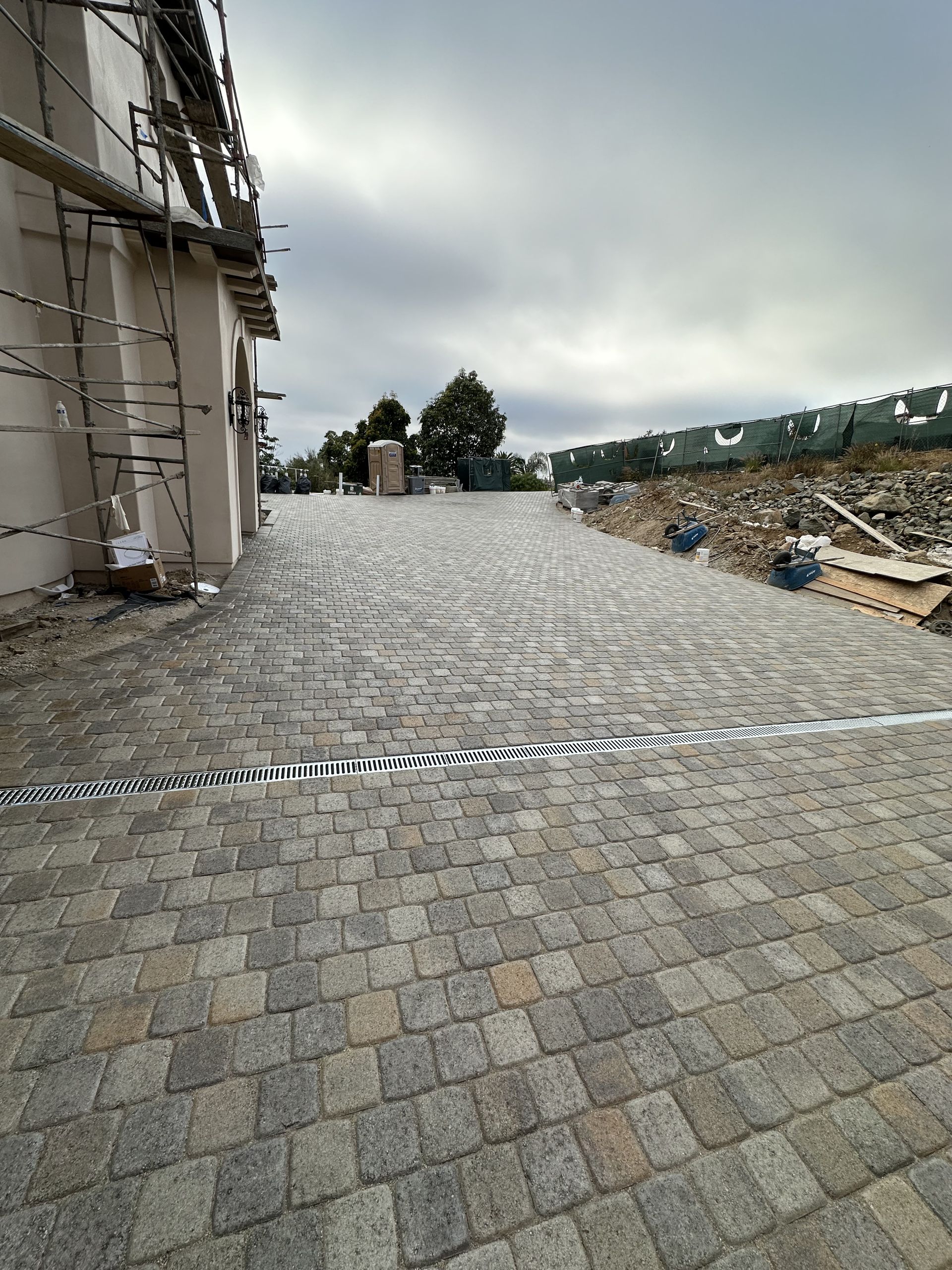 A brick driveway leading to a building under construction