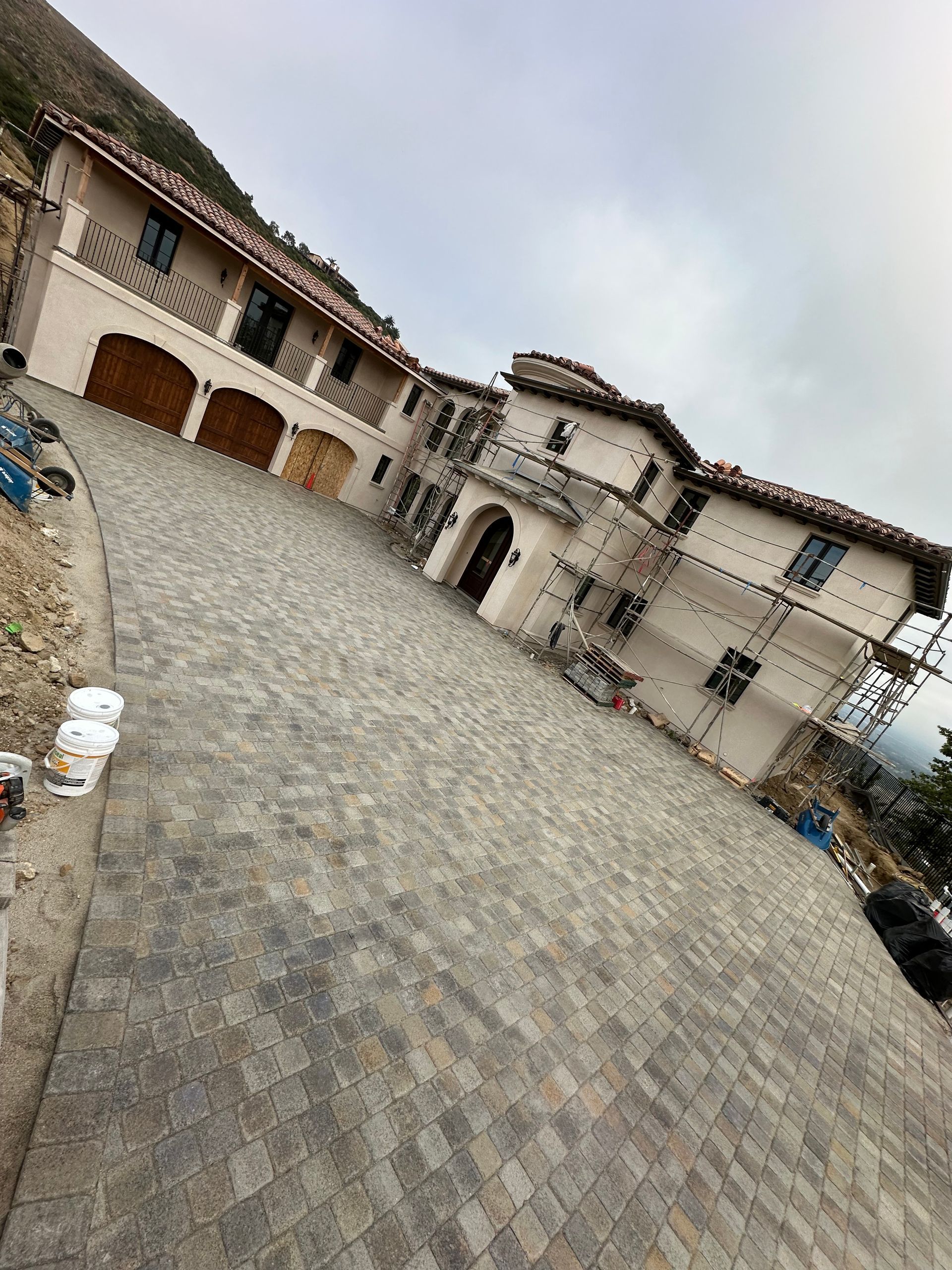 A large white house with a brick driveway in front of it.