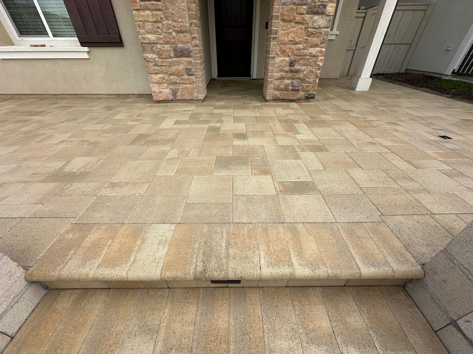A brick walkway with steps leading to the front door of a house.