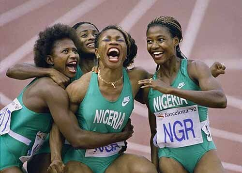Nigerian women's relay team celebrating victory, wearing green uniforms, arms raised, on a track.