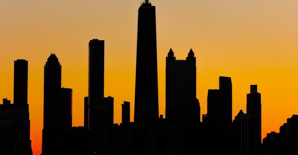 Silhouette of a city skyline against an orange and yellow sunset.