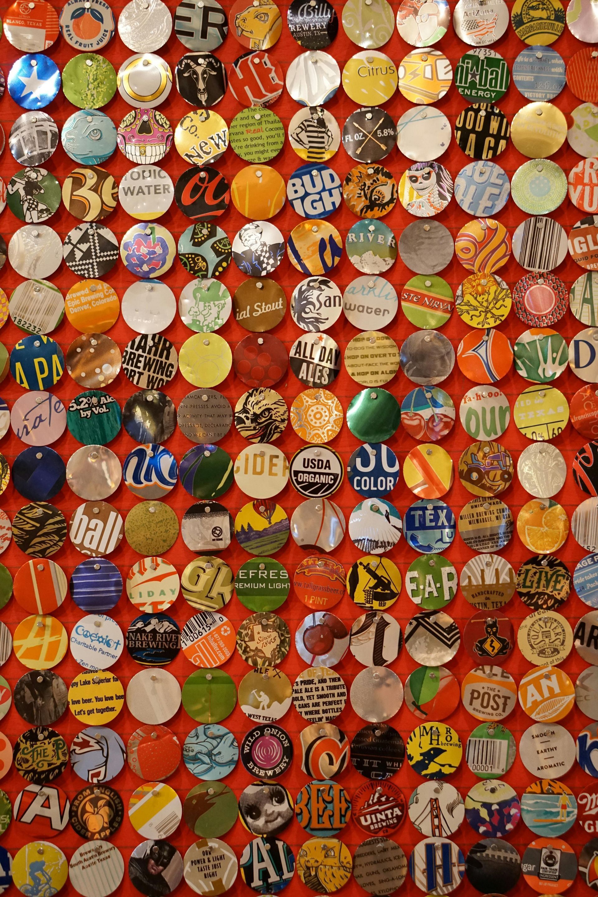 Wall covered in colorful bottle caps of various brands.