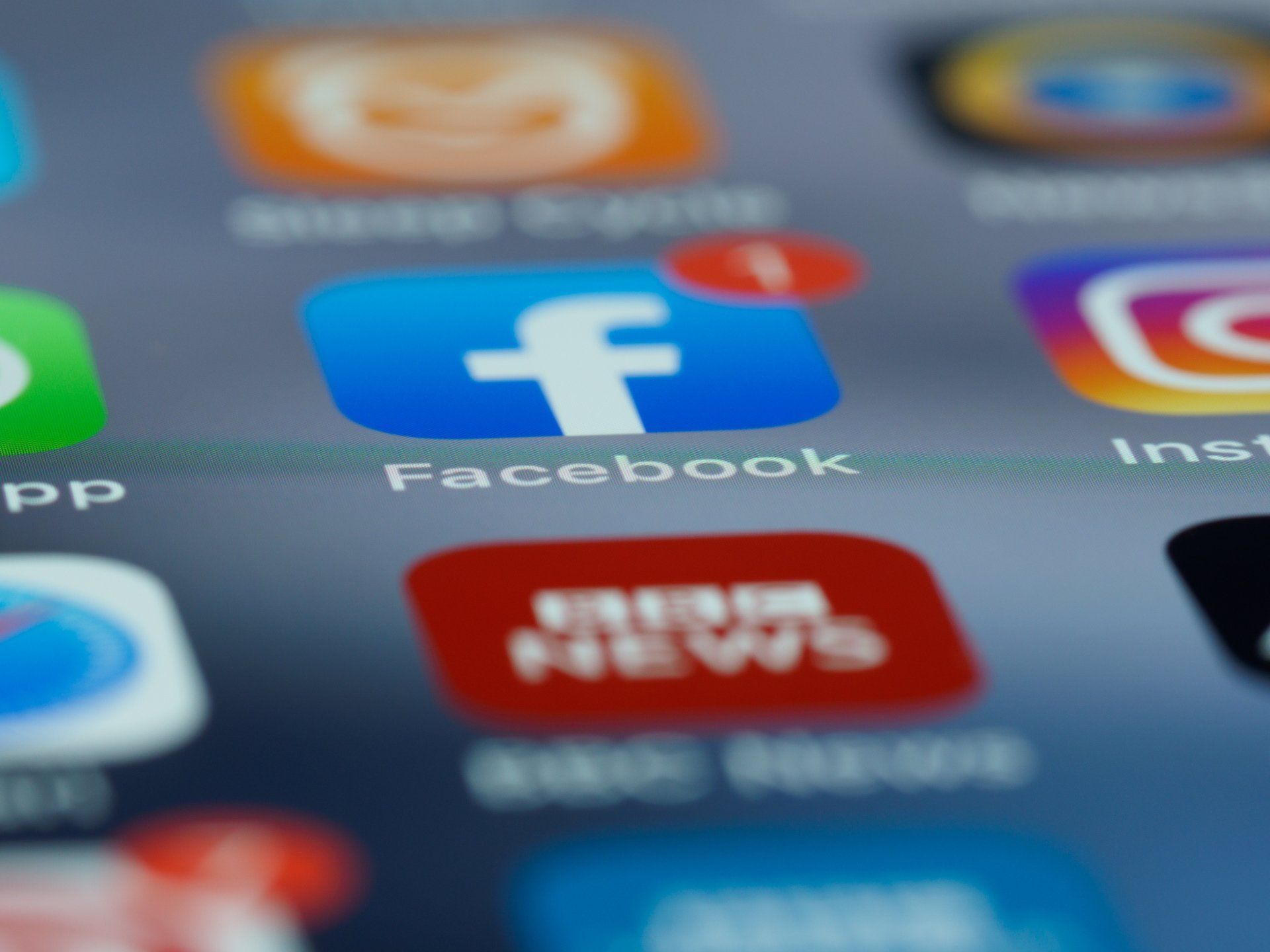 Facebook app icon on a phone screen, surrounded by other social media app icons.