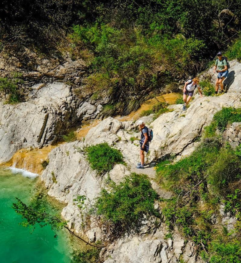 Een persoon i zit op een grote rots bij een helderblauwe, transparante canyon in Rochetta Nervina 