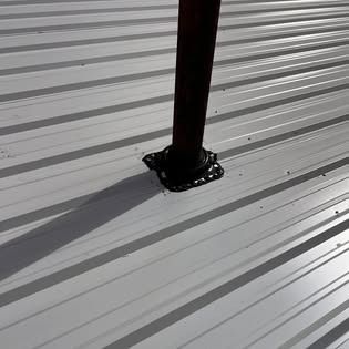 A metal roof with a pipe in the middle of it.