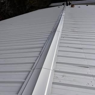 A white metal roof with a gutter on the side of it.